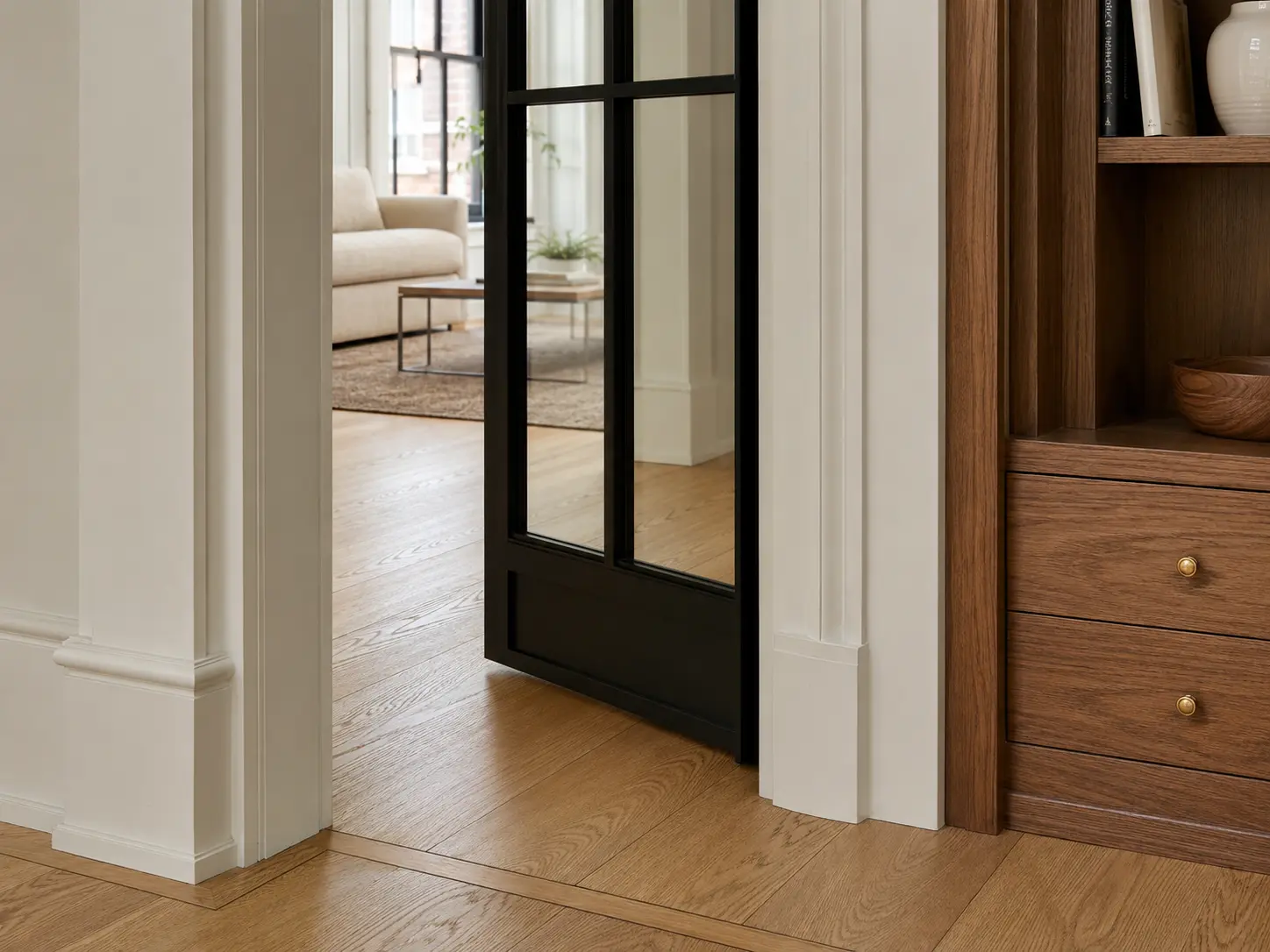 Representative close view of renovated millwork, oak floor and a black-framed interior door